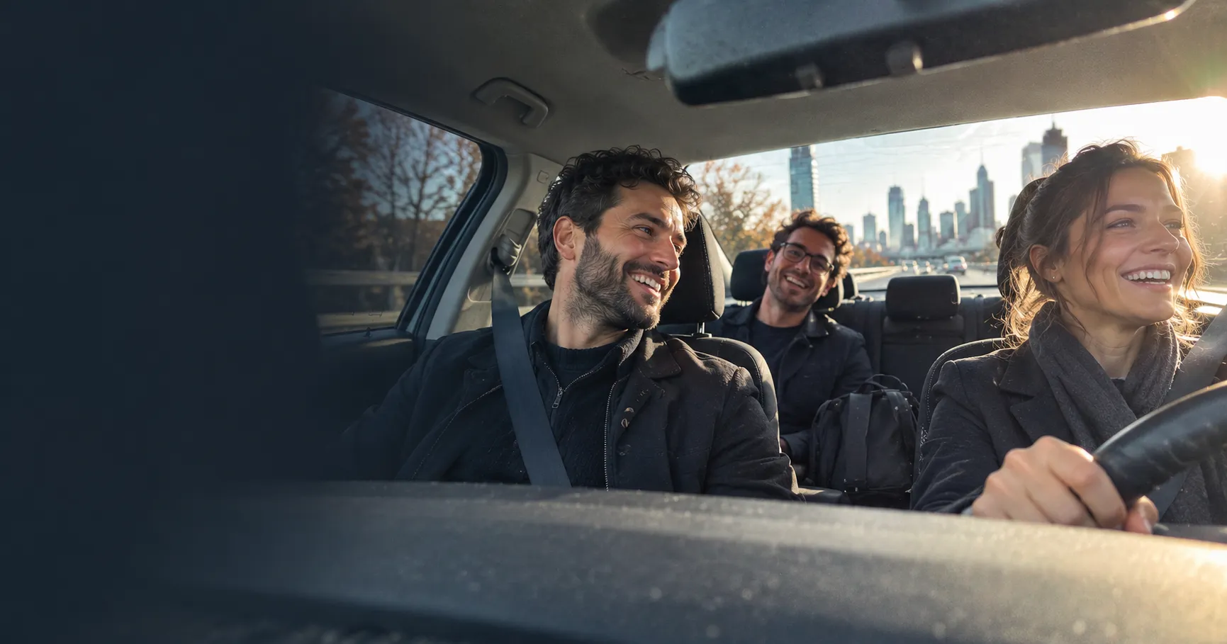 Trois collègues partagent une voiture pour aller travailler, souriants, avec une ville devant eux